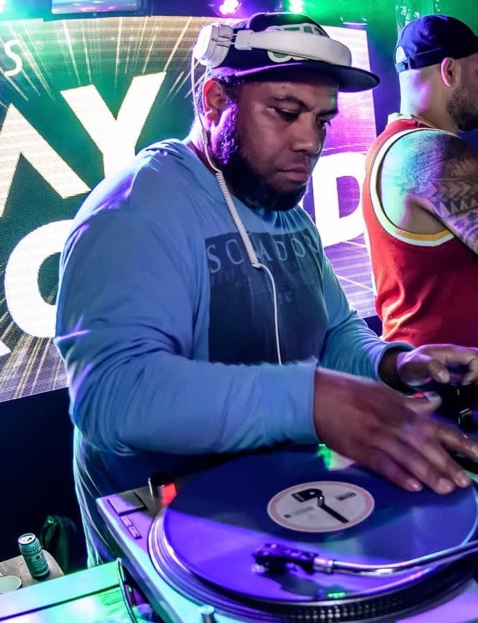 DJ Static mixing behind the decks under club lighting